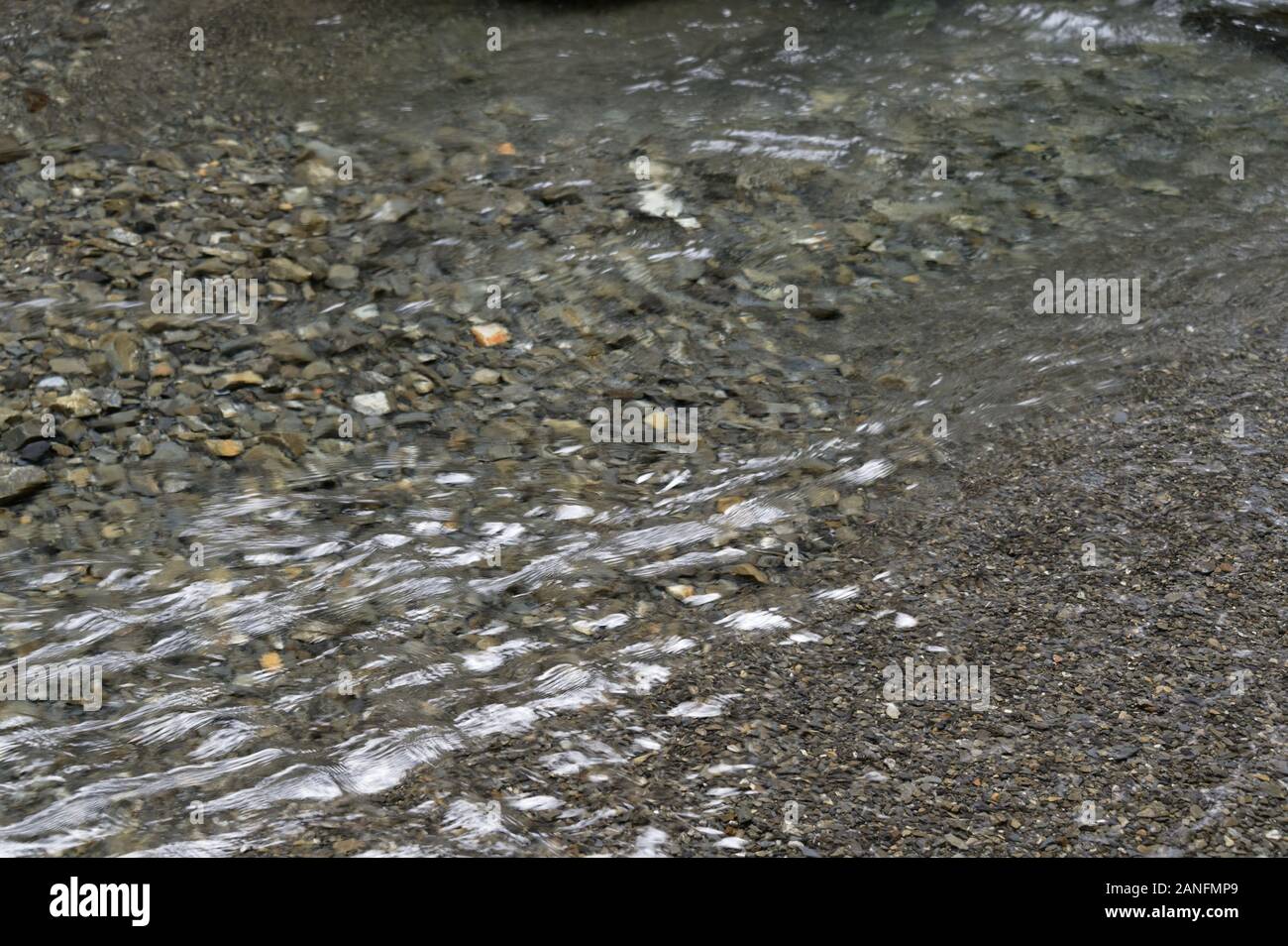 Graue Steine bilden das Bett eines seichten Fluss Stockfoto