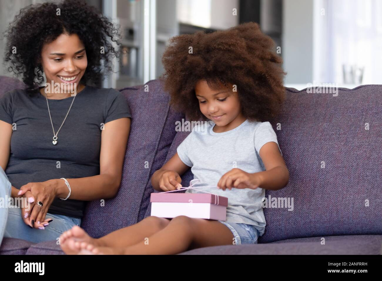Süße kleine schwarze Mädchen auspacken Geburtstagsgeschenk zu Hause Stockfoto