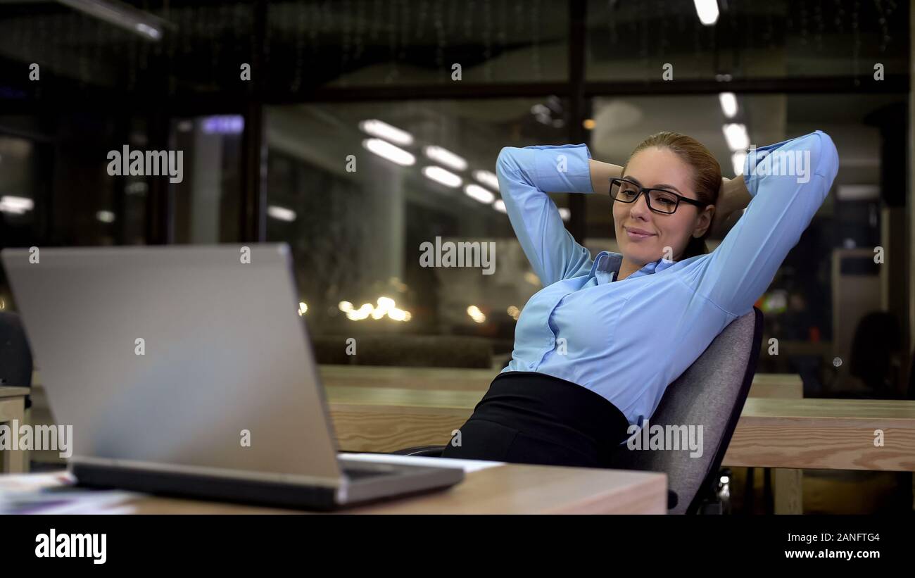 Produktive Geschäftsfrau lehnte sich zurück nach Abschluss der Arbeiten am Laptop Stockfoto