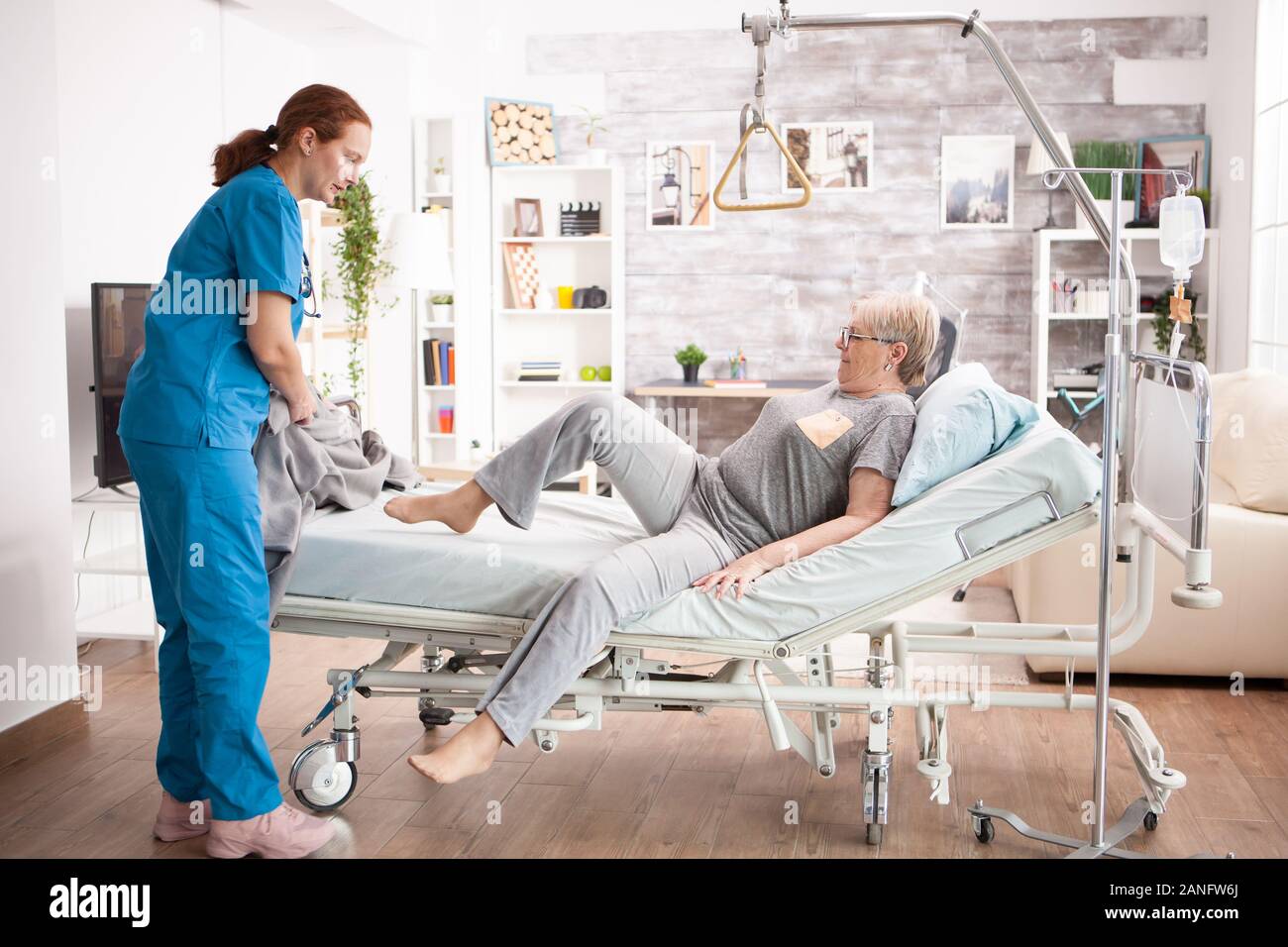 Alte Frau im Pflegeheim Verlegung auf Bett mit Hilfe von Gesundheit Besucher. Stockfoto