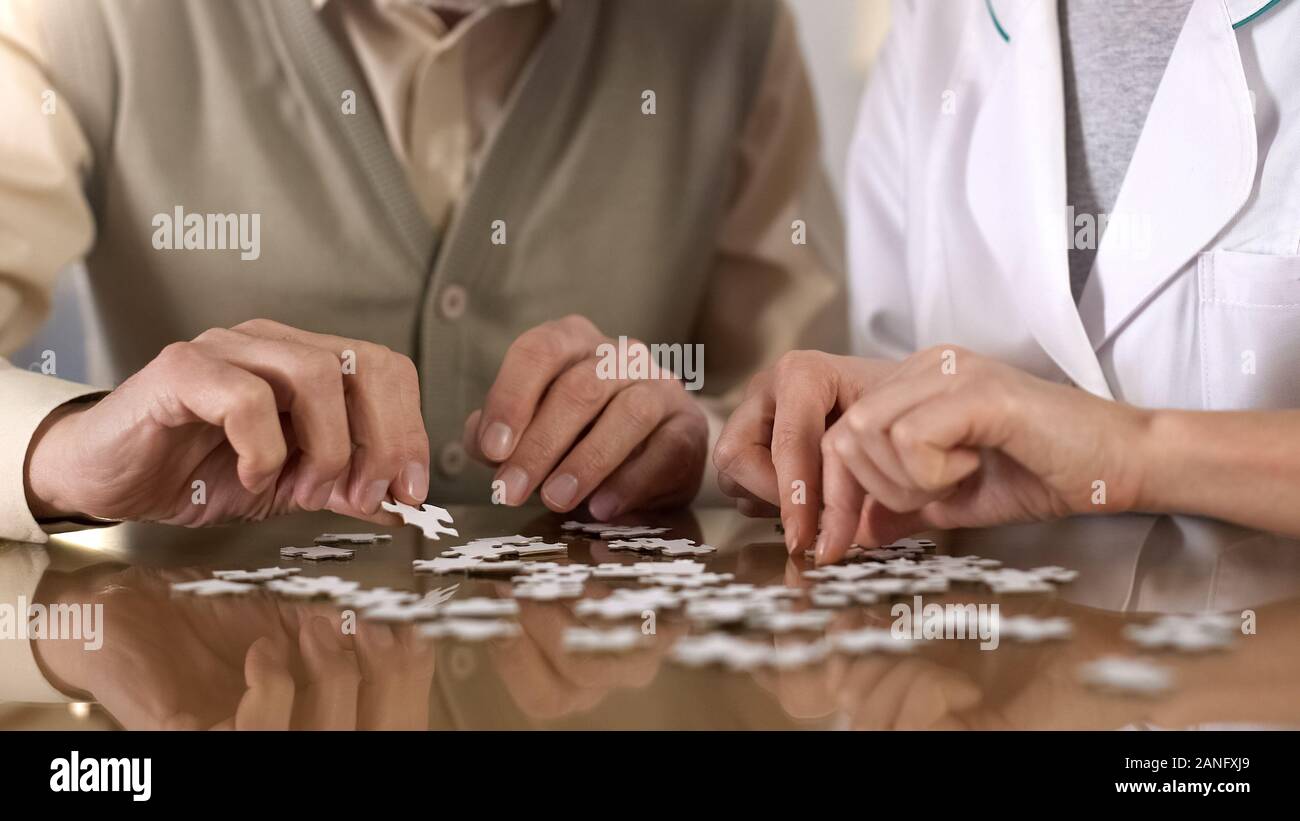 Weibliche Betreuer helfen, alter Mann tun puzzle Tabelle, Mentaltraining, Alzheimer Stockfoto