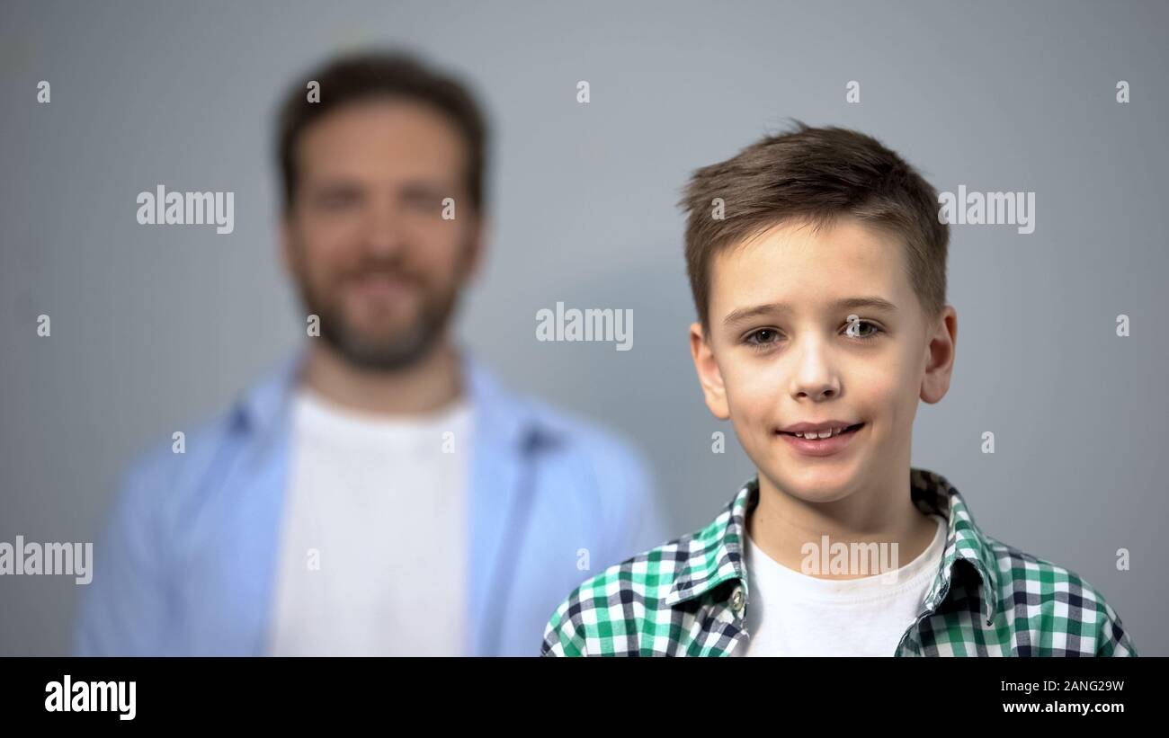 Junge lächelnd an Kamera, Vater stehen auf Hintergrund, Familie, Pflege und Unterstützung Stockfoto