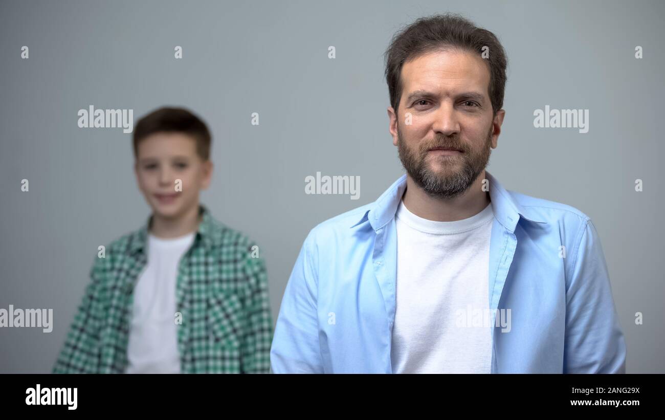 Mann mittleren Alters lächelnd an kleinen Jungen hinter der Kamera stehen, Kindheitserinnerungen Stockfoto