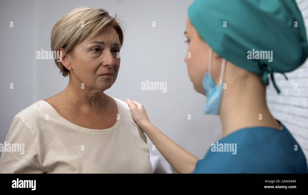 Weibliche Krankenschwester erzählen Patienten schlechte Diagnose, enttäuschenden Nachrichten, Frau weinen Stockfoto