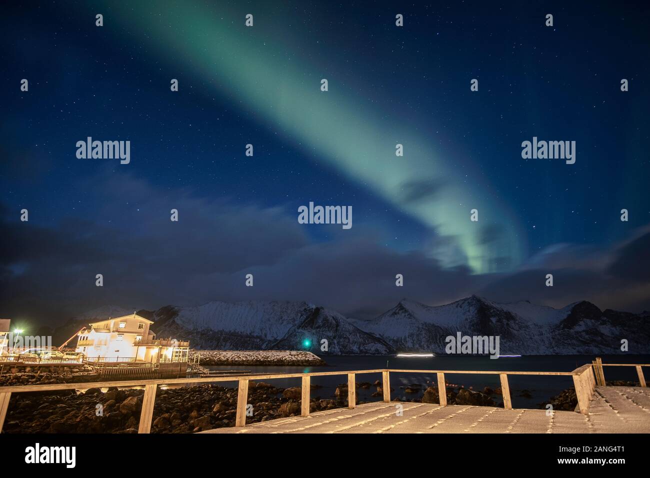 Aurora borealis oder Northern lights über verschneite Berge mit Haus Beleuchtung in Mefjord Brygge, Senja Island, Norwegen Stockfoto