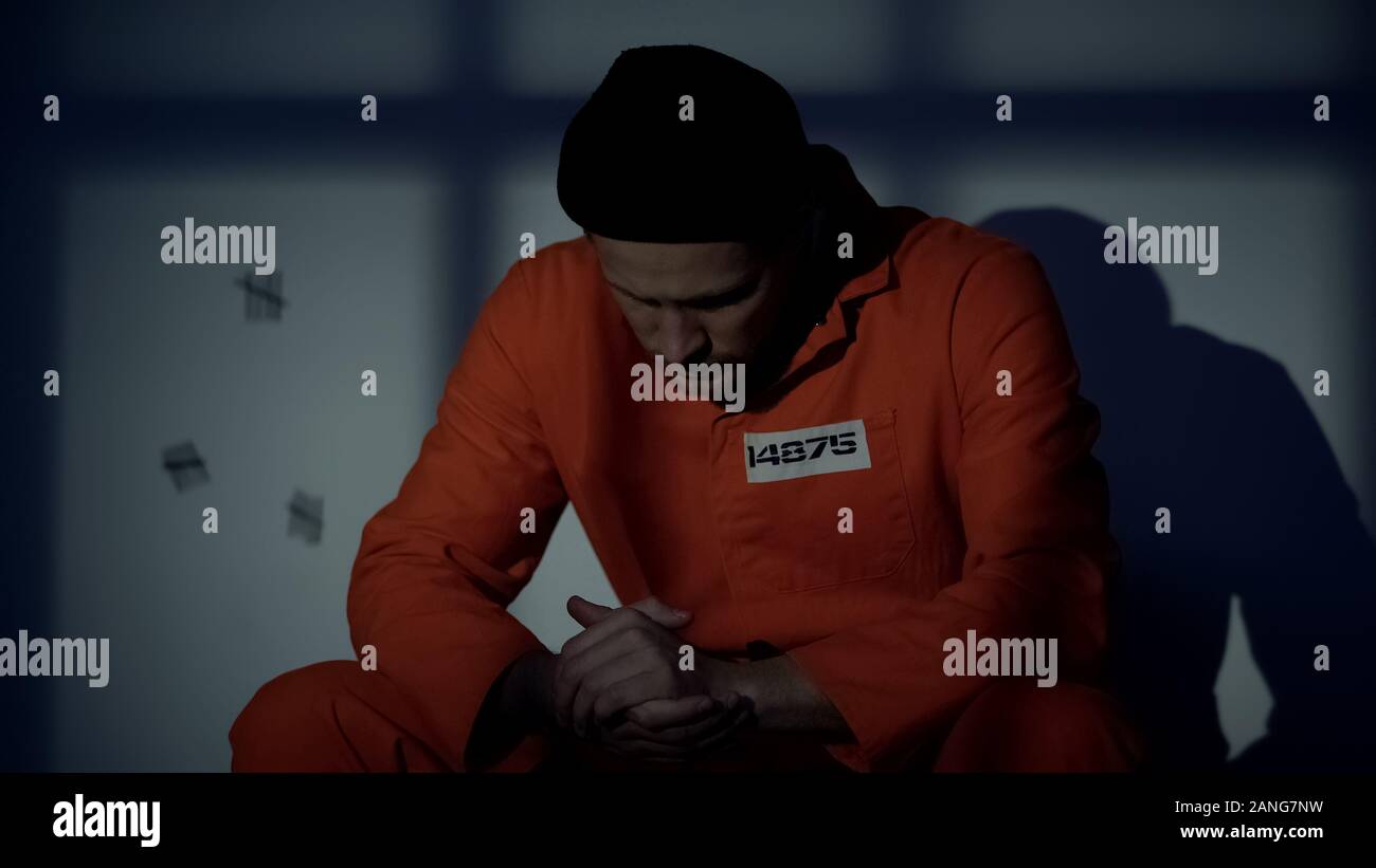 Männliche Kaukasische Gefangene in der Zelle sitzen, fühlen sich schuldig über Verbrechen, Überzeugung Stockfoto