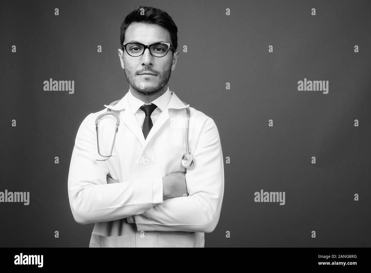 Junge schöne Hispanic Mann Arzt gegen grauer Hintergrund Stockfoto