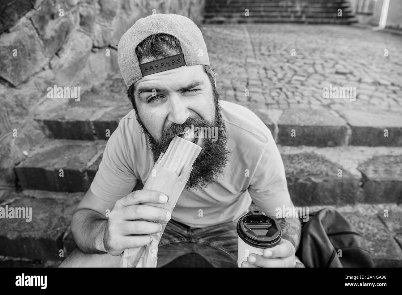 Bessere Zutaten, bessere Küche. Bärtiger Mann essen ungesundes fast food Küche. Kaukasische Kerl Reisende genießen Straße Küche. Hipster in Tra Stockfoto