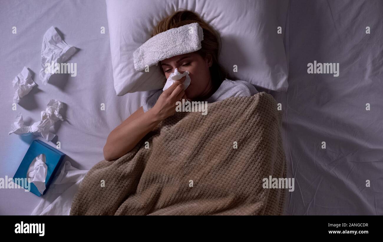 Kranke Frau mit compress und Servietten im Bett lag, Niesen, saisonale Allergien Stockfoto