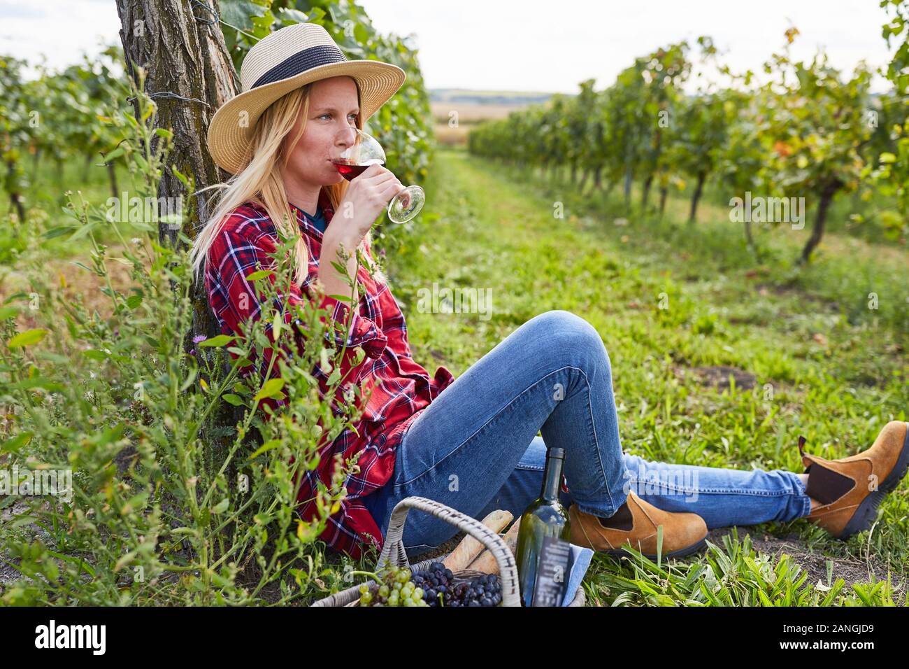 Junge Frau als Winzer oder Ernten Helfer Getränke ein Glas Rotwein im Weinberg Stockfoto