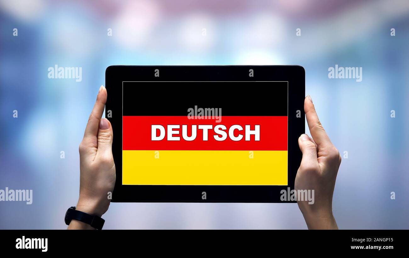 Weibliche Hände, die Tablette mit deutschen Wort gegen die nationale Flagge, online App Stockfoto