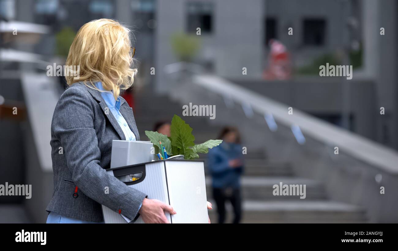 Business Lady mit Material Box am Bürogebäude suchen, Rente Arbeitslosigkeit Stockfoto