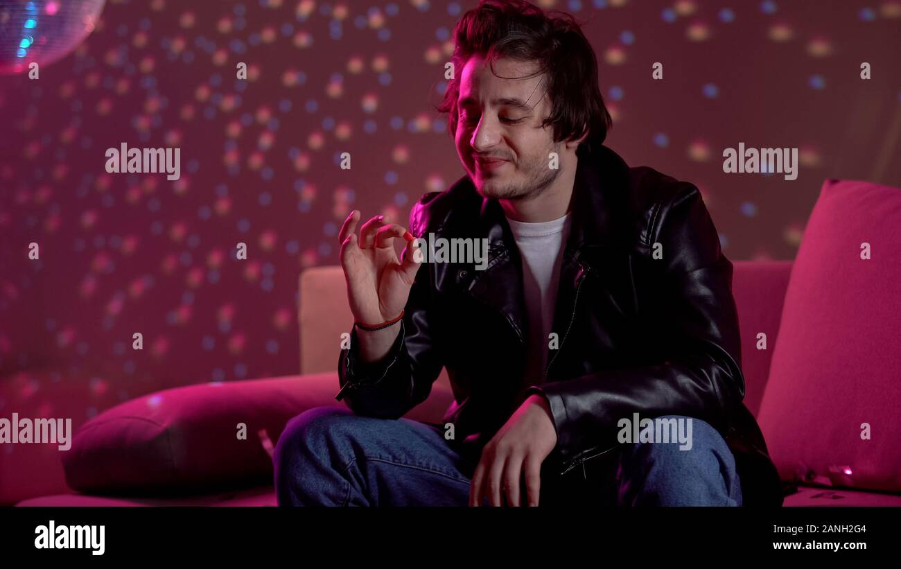 Junger Mann mit Ecstasy Pille, Spaß an der Rave Party, Club Drogen süchtig Stockfoto