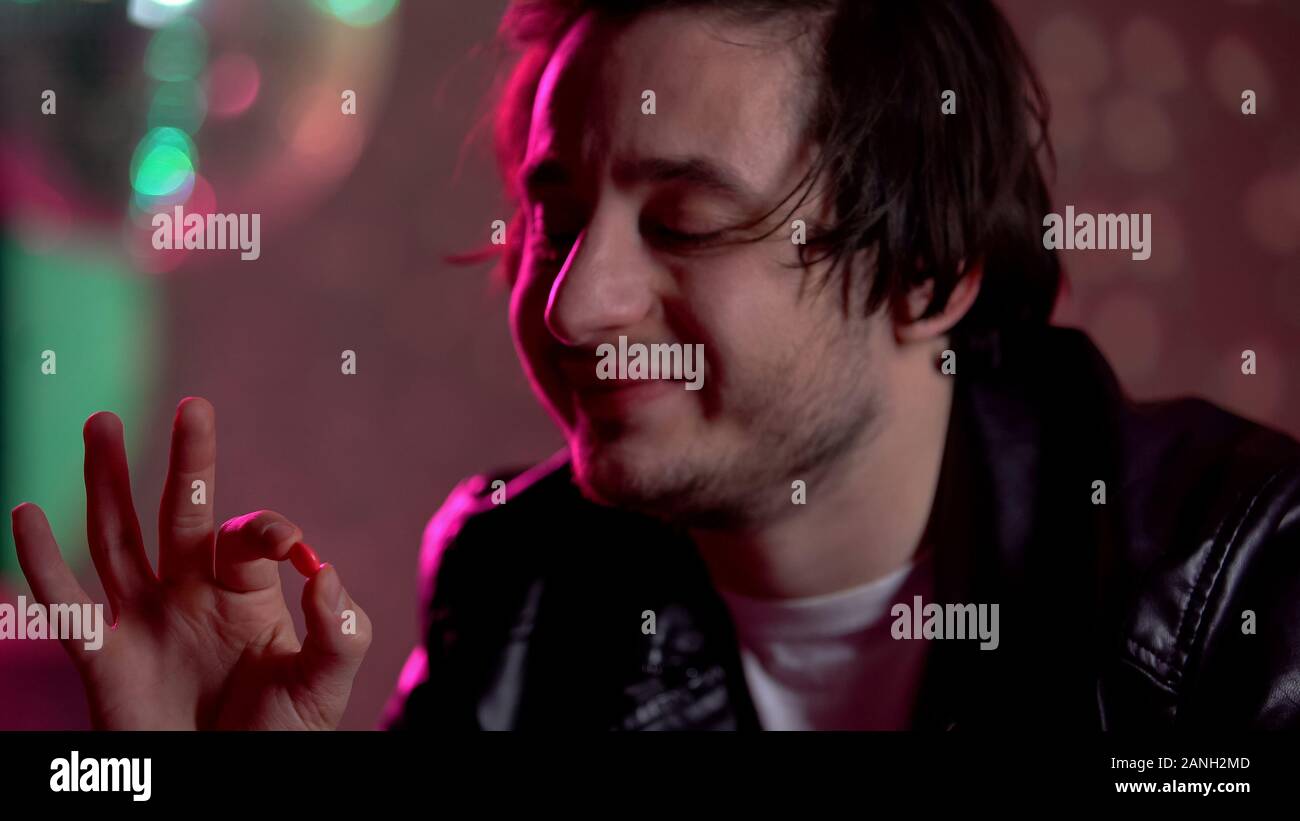 Männliche clubber Holding ecstasy Pille, Neigung zu Drogen, Rausch Stockfoto