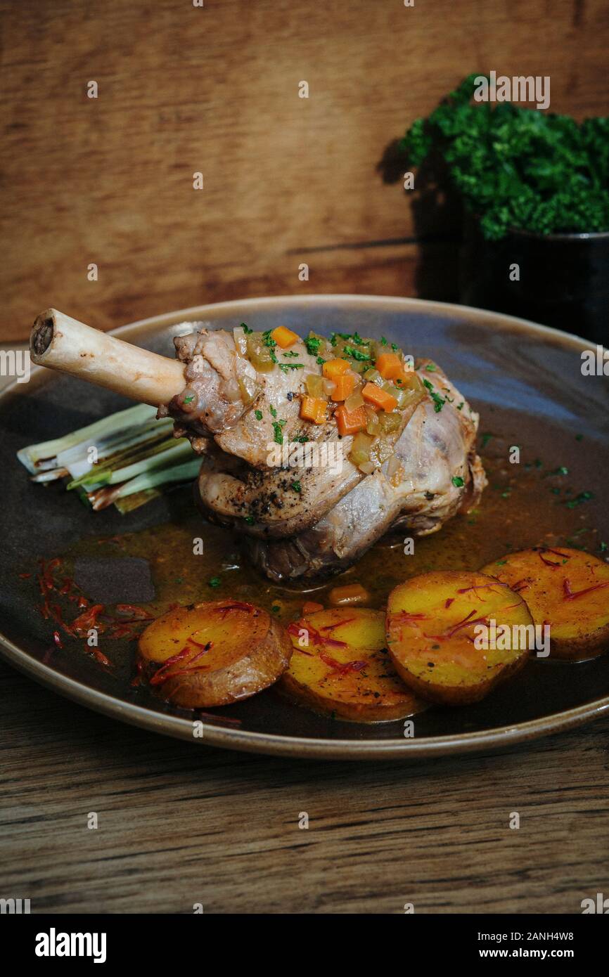 Braten Sie das Abendessen. Hauptgericht gebratener Lamb-Schaft mit Safrankartoffeln und Lauch, Holzhintergrund Stockfoto