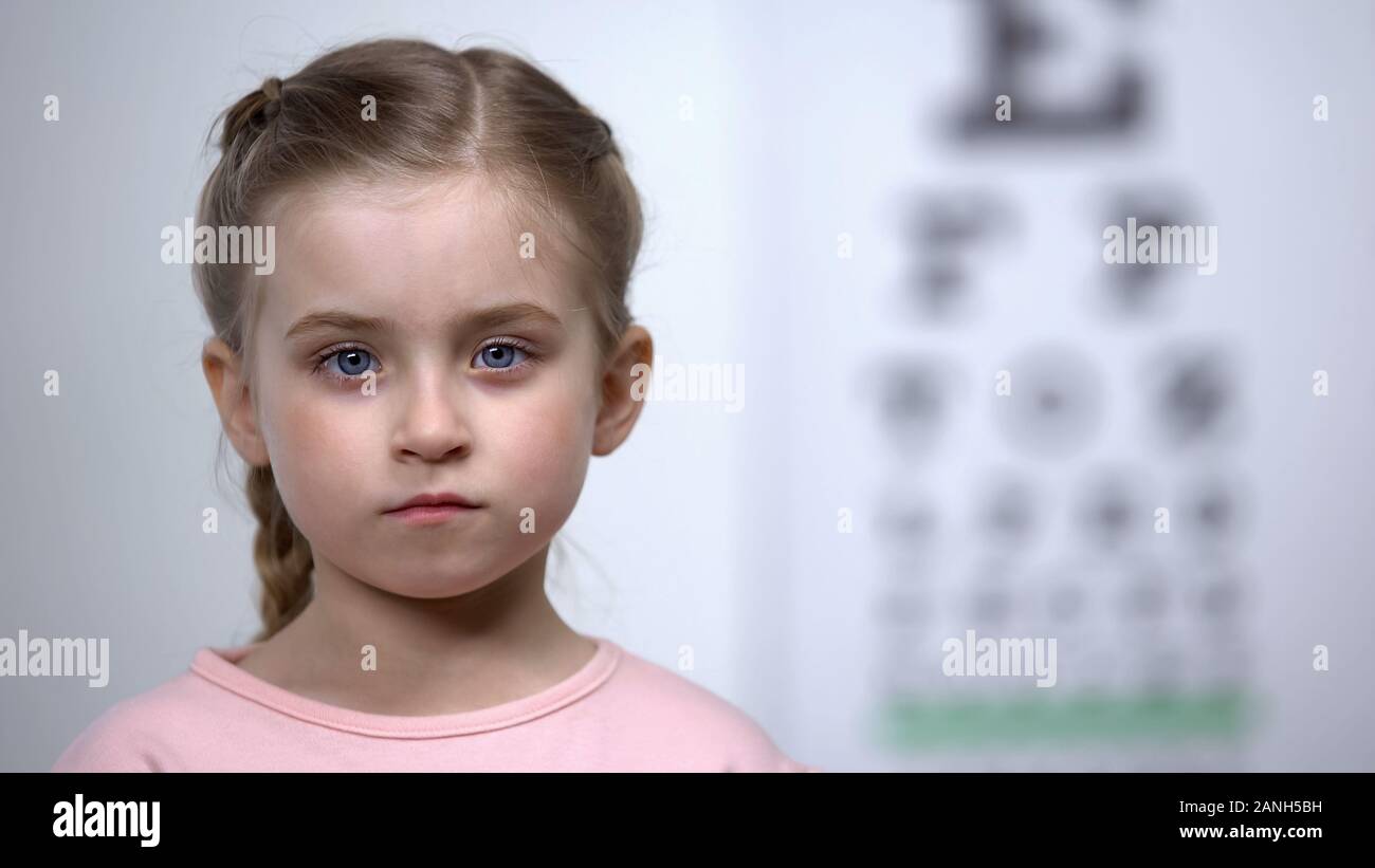 Süße kleine Mädchen stehen auf Hintergrund der Sehschärfe testen Tabelle, Optik Stockfoto