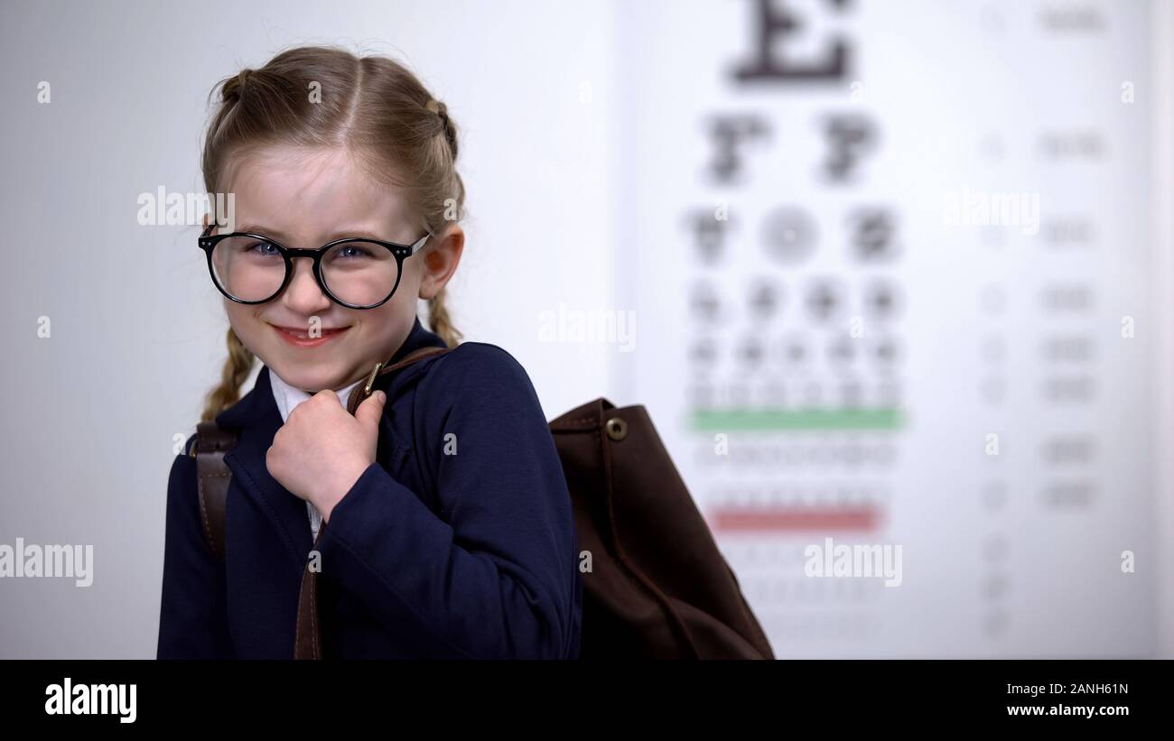 Hübsche Schülerin in Gläser Lächeln, das Bewusstsein für vollständige Augenuntersuchung vor der Schule Stockfoto