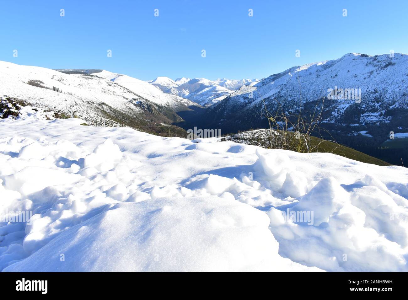 Winterlandschaft mit Schnee bedeckten Bergen und grünen Tal. Blick von einem Spitzenwert von Eis, Schnee und blauer Himmel. Ancares Region, Provinz Lugo, Galizien, Spanien. Stockfoto