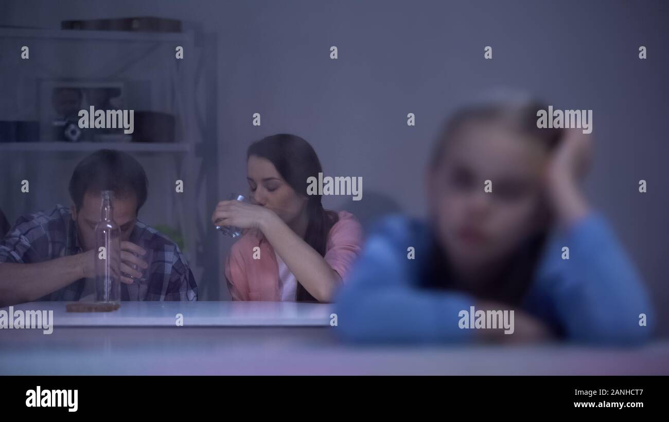 Trauriges Mädchen Blick durch Fenster, Eltern Wodka zu trinken auf den Hintergrund, sucht Stockfoto