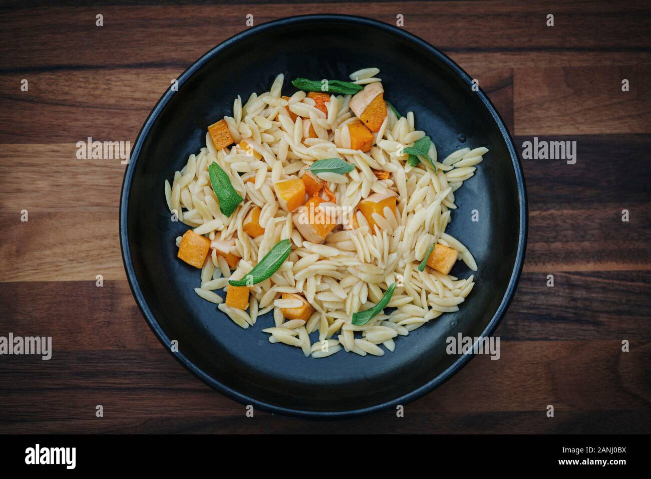 Veganer Hauptgang: Orzo Pasta mit Butternusskürbis und Salbei. Vegetarische Lebensmittel - flaches Lay/Draufsicht. Stockfoto