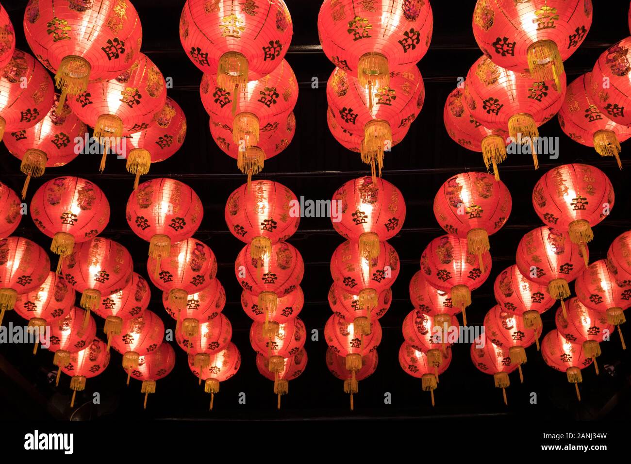 Eine Gruppe roter Laternen an der Decke. Jede Laterne hat chinesische Alphabete, die den Wunsch nach viel Glück und Glück bedeuten. Stockfoto