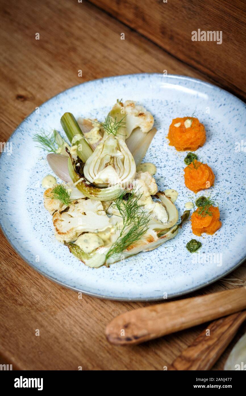 Veganer Hauptgang: Blumenkohlsteak mit Fenchel und Karottenpüree. Holzhintergrund und Draufsicht. Vegetarisches Essen Stockfoto