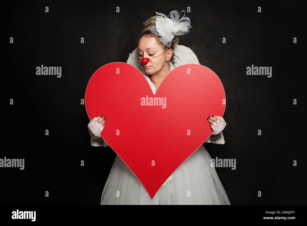 Schauspielerin Dame in Clown Kostüm mit roten Herzen auf schwarzem Hintergrund Stockfoto