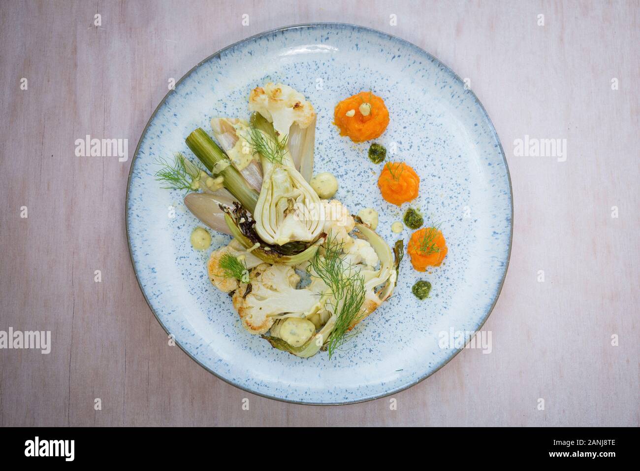 Veganer Hauptgang: Blumenkohlsteak mit Fenchel und Karottenpüree. Holzhintergrund und Draufsicht. Vegetarisches Essen Stockfoto
