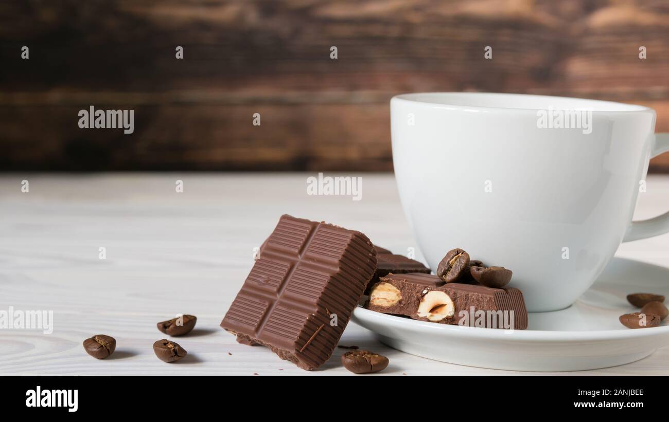 Stücke Schokolade mit Haselnüssen und Kaffeebohnen auf einem braunen Tischdecke Stockfoto