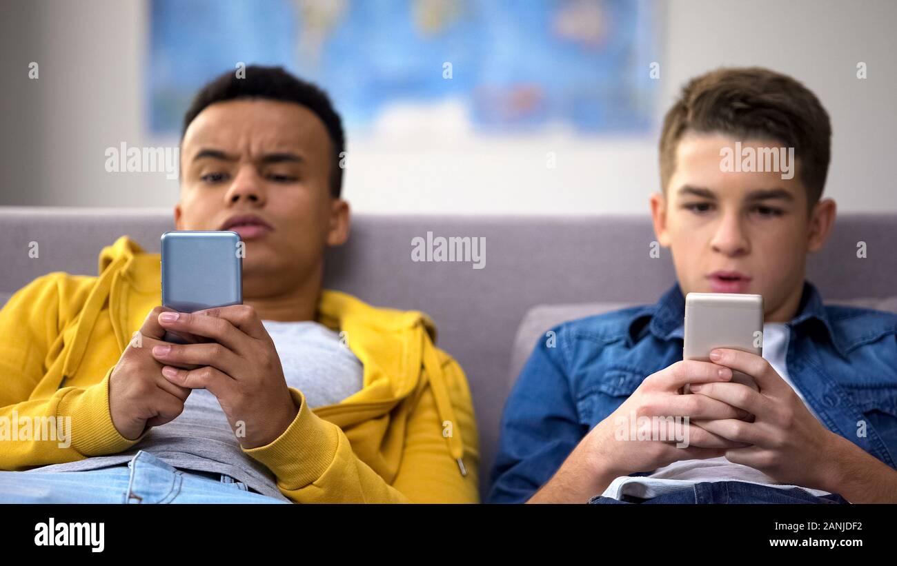 Männliche Jugendliche lesen Schockierende Neuigkeiten in sozialen Netzwerken, moderne Technologie Stockfoto