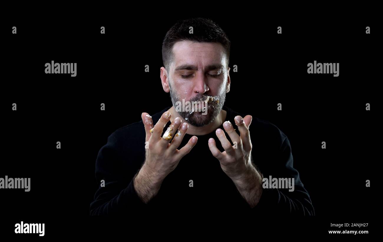 Zufrieden Mann mit Kuchen Creme auf Hände, psychologisches Problem, Essstörung Stockfoto