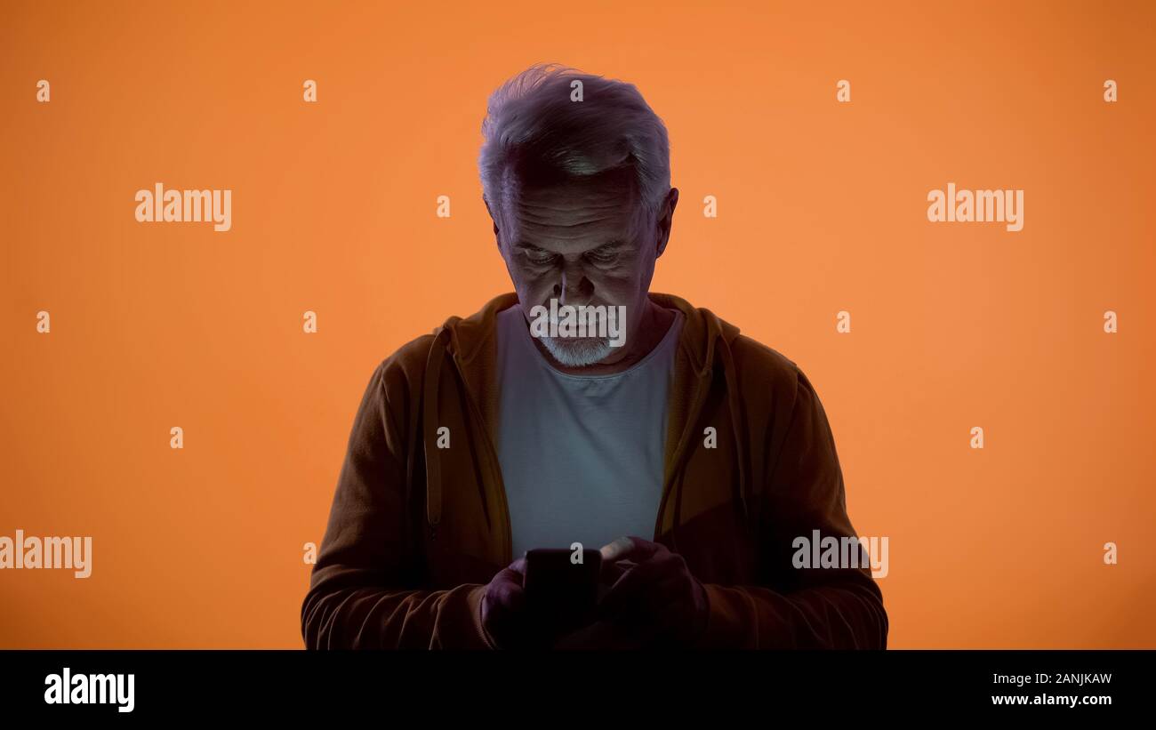 Alter Mann eingeben Nachricht auf dem Smartphone, orange Hintergrund, Vision Problem umgekippt Stockfoto