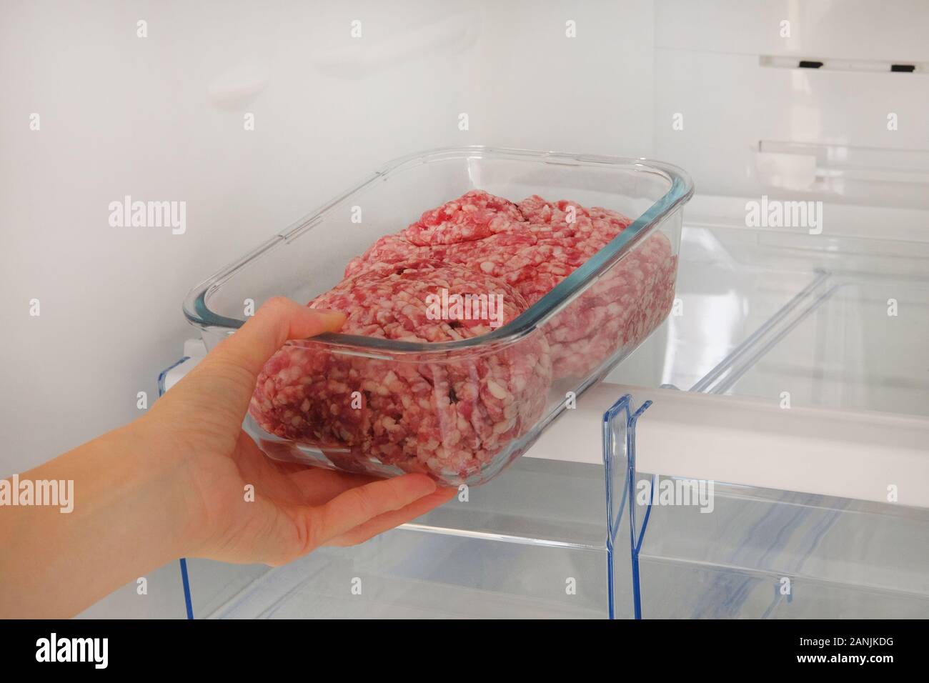 Hackfleisch/Faschiertes rohes Fleisch im Glas Container ist im Regal in  offenen Kühlschrank. Weibliche Hand zieht sich aus dem Kühlschrank eine  Zutat für das Kochen von Fleisch Stockfotografie - Alamy