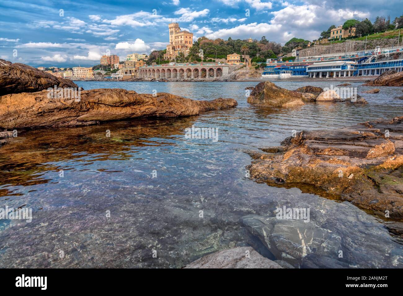 Ruhigen rock Pool mit Blick auf die Waterfront Gebäuden und historischen Quarto Wahrzeichen an der Italienischen Riviera Küste unter einem bewölkten Himmel Stockfoto