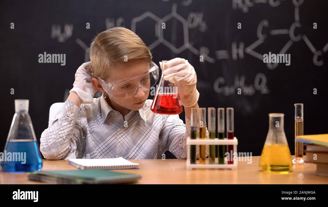 Schüler auf der Suche nach rote Flüssigkeit im Kolben und kratzen Kopf, keine Ahnung Stockfoto