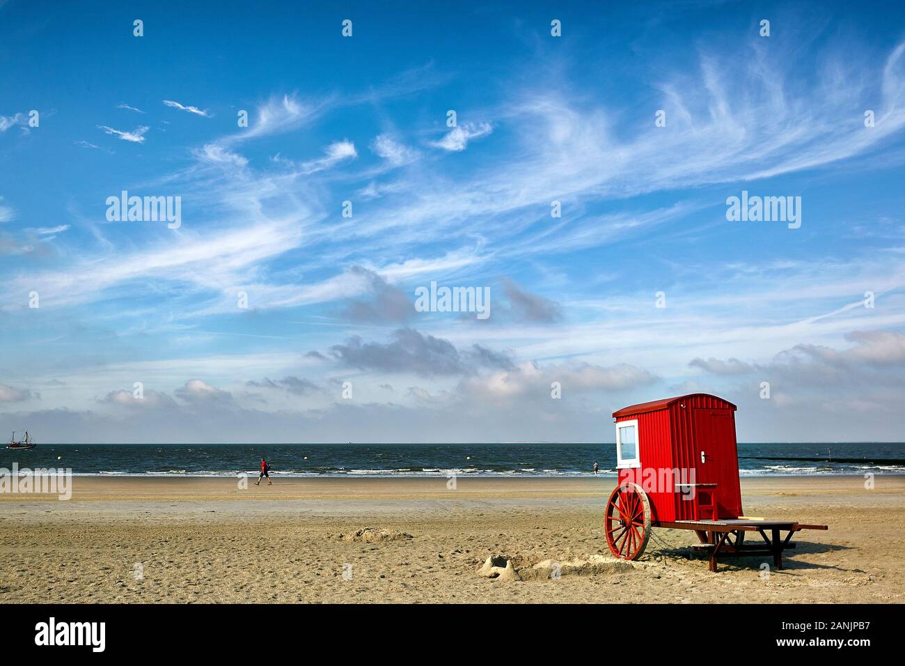 Rot bemalte Strandwechselkabine aus Holz auf Rädern am Borkum-Südstrand mit zirrusigen Wolken am Himmel Stockfoto