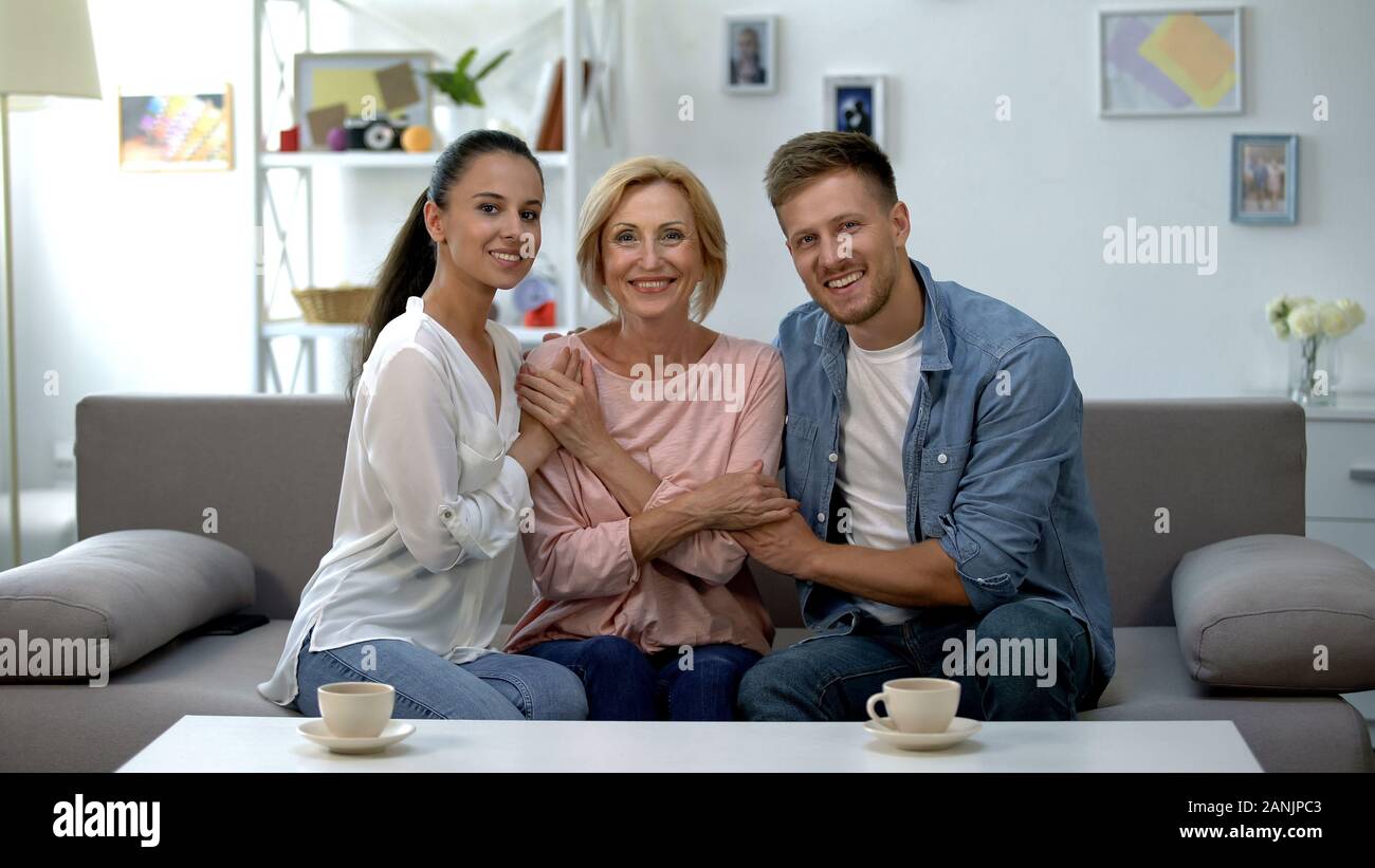 Junges Paar und Schwiegermutter halten sich an den Händen und lächelte Kamera, glücklich zusammen Stockfoto