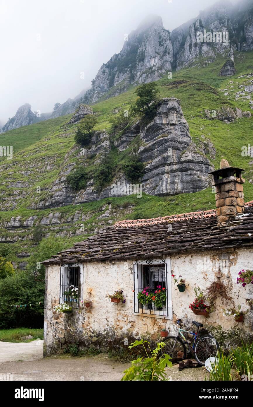 Traditionelles Steinhaus am Fuße der Kalksteinauswüchse im Tal Valle del Miera (San Roque de Riomiera, Valles Pasiegos, Kantabrien, Spanien) Stockfoto