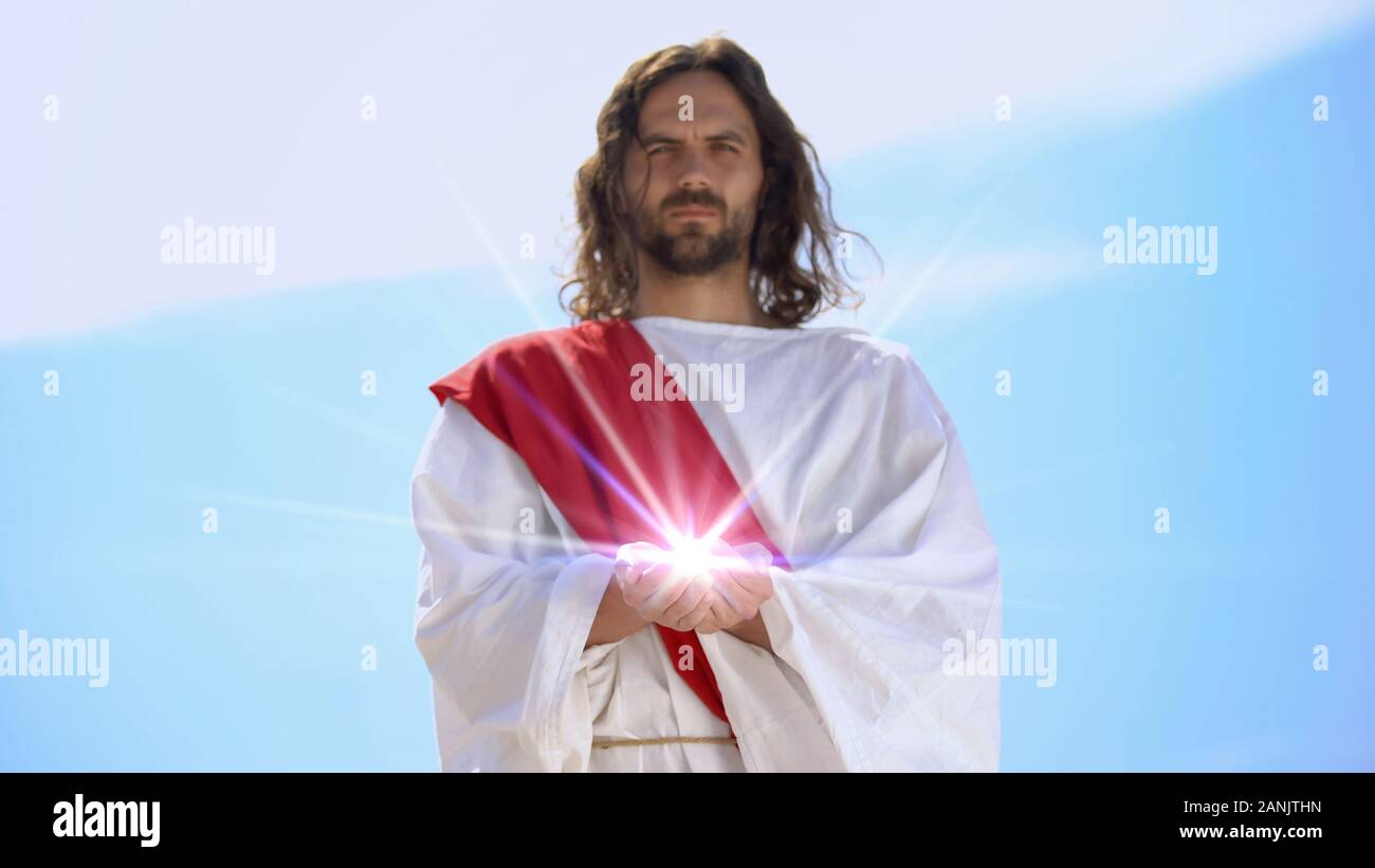 Jesus Holding spirituelles Licht gegen Himmel, Konzept der Heilung, religiöse Wunder Stockfoto