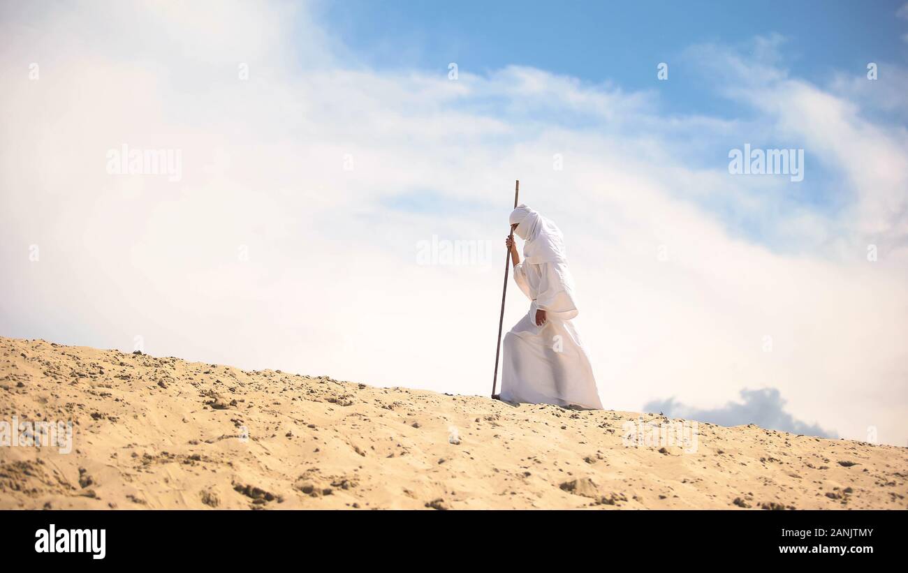 Müde Beduinen mit Personal wandern in heißen Wüsten, Klimawandel, globale Erwärmung Stockfoto