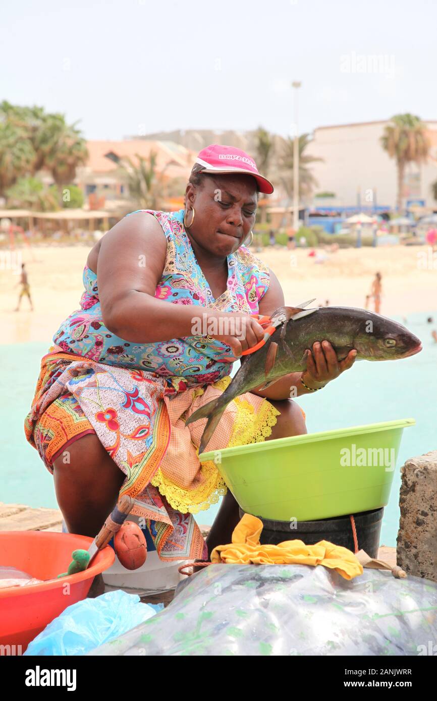 Lokale Frau, die auf traditionelle Weise auf dem Fischmarkt auf dem Pier in Santa Maria, Sal, Kap Verde, Fisch auszog und zubereitete Stockfoto