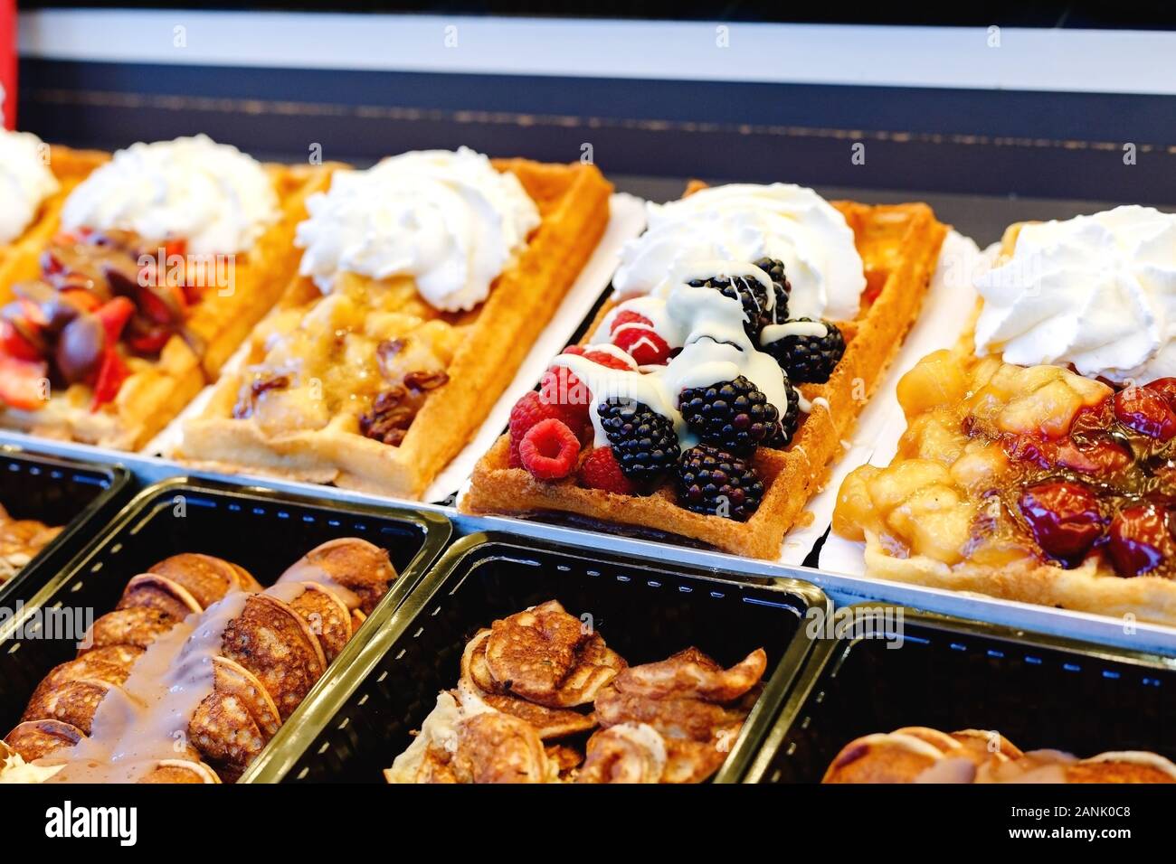 Belgische Waffeln Street Food mit verschiedenen Toppings, Obst, Süßigkeiten, Schlagsahne. Schaufenster Konditorei Belgische Waffeln von verschiedenen Arten. Foto Stockfoto