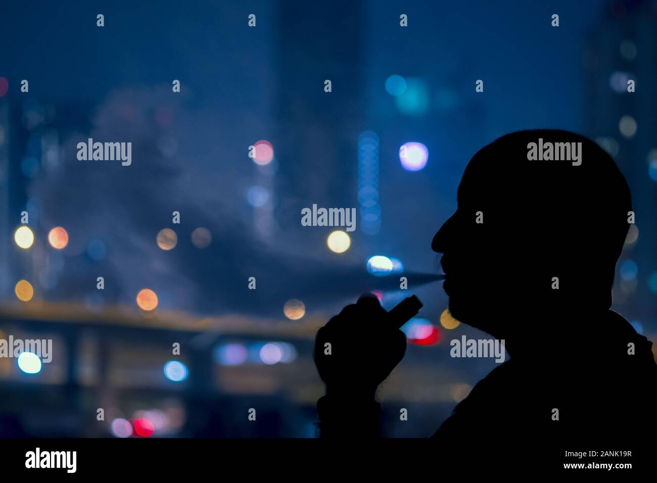 Mann mit Elektronische Zigarette und Rauch vapping mit Stadt bokehlights Hintergrund helfen Rauchtabak beenden Stockfoto