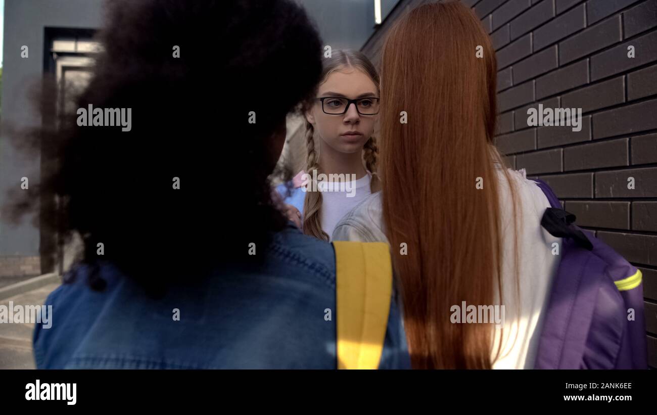 Weibliche Studenten stehen vor der Schulfreund in Brillen im Hinterhof, Konflikt Stockfoto