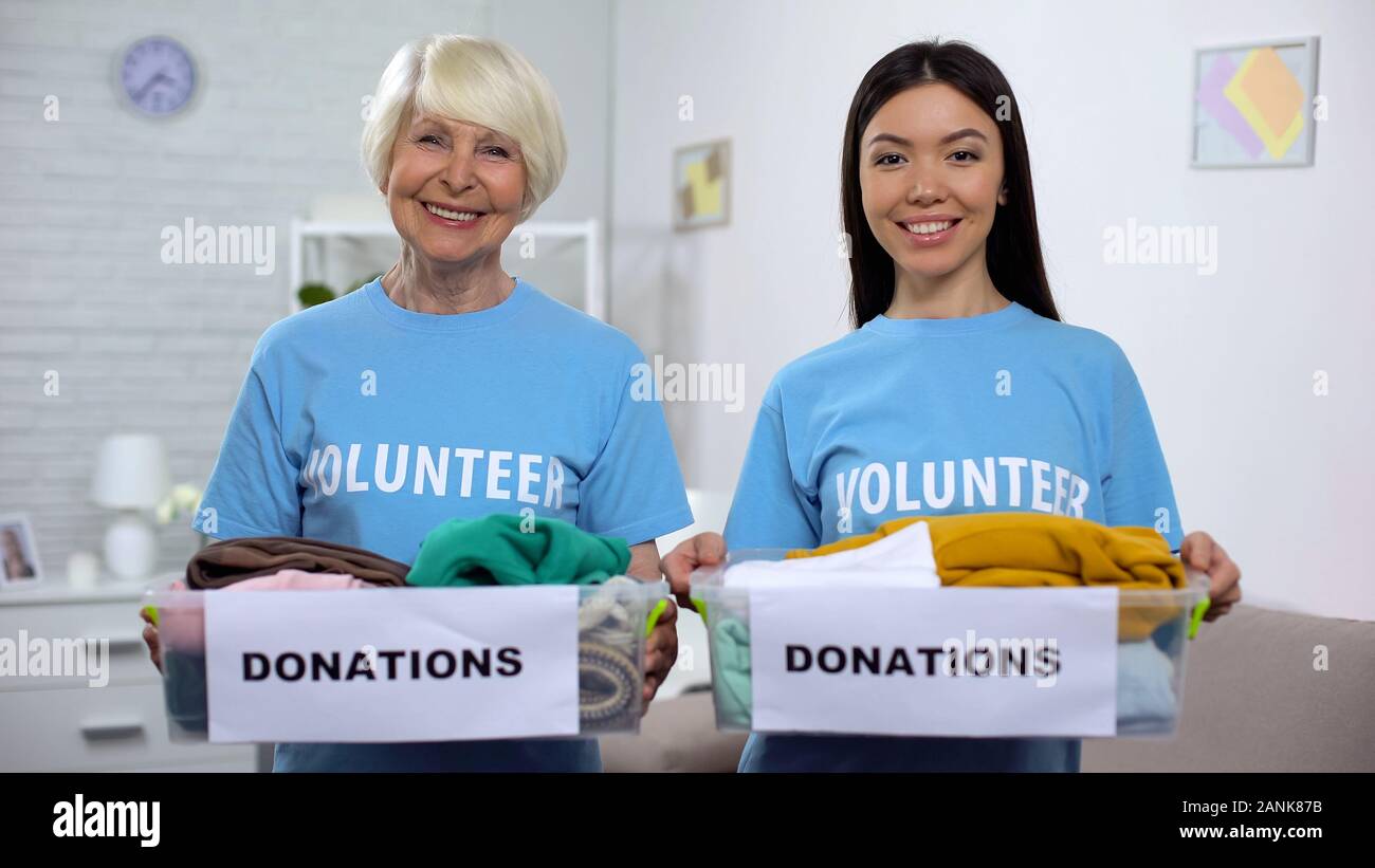 Cheerful female volunteers holding donation boxes, humanitarian aid, assistance Stockfoto