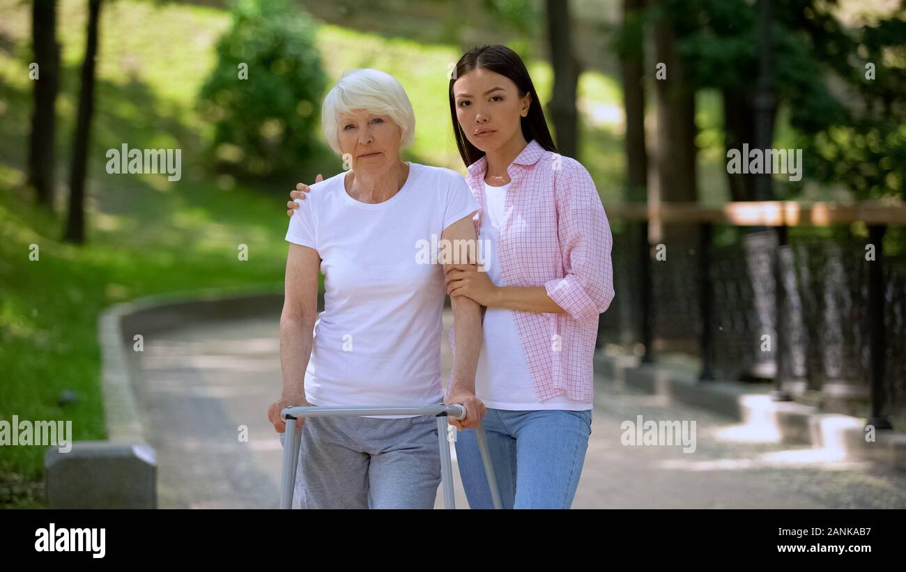 Traurig alter Patient Gehhilfen und Tochter suchen Kamera, soziale Unsicherheit Stockfoto