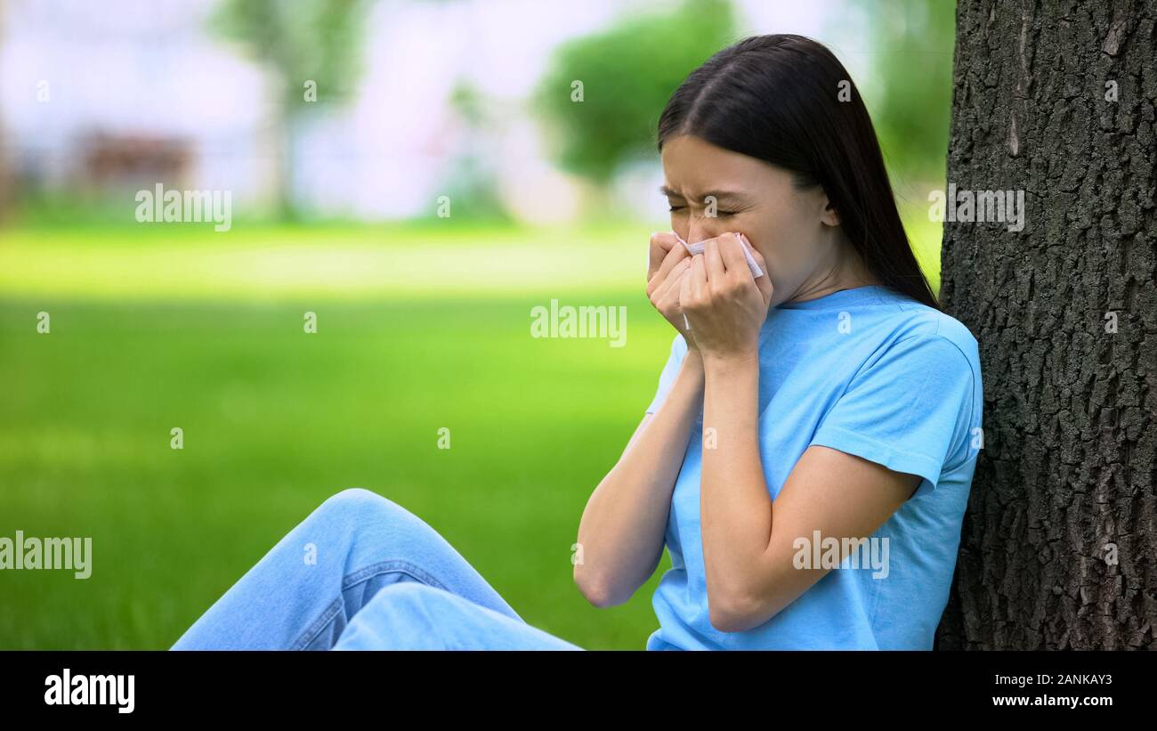 Niesen Frau sitzt im Freien leiden saisonale Allergien, Gesundheitswesen, Symptom Stockfoto