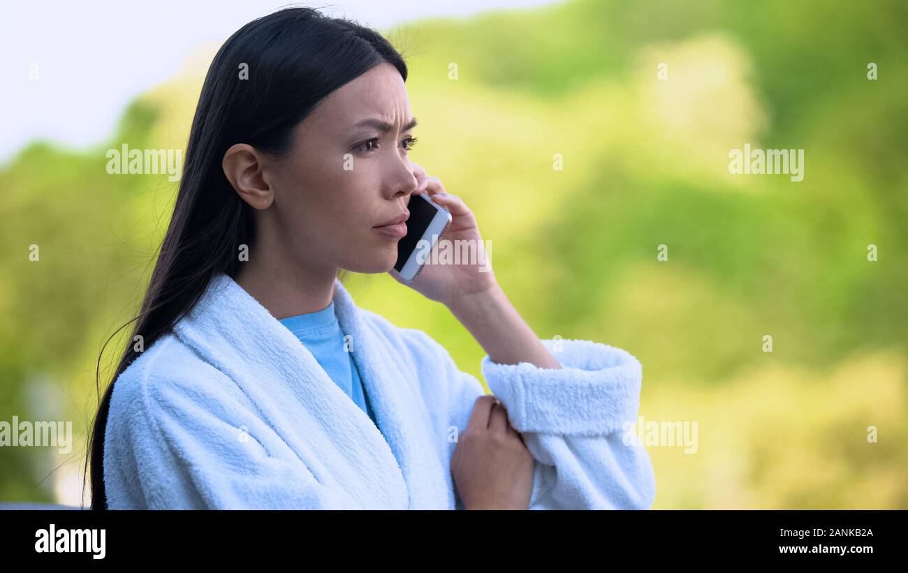 Junge Frau im Bademantel am Telefon sprechen im Freien, betonte der Problem umgekippt Stockfoto