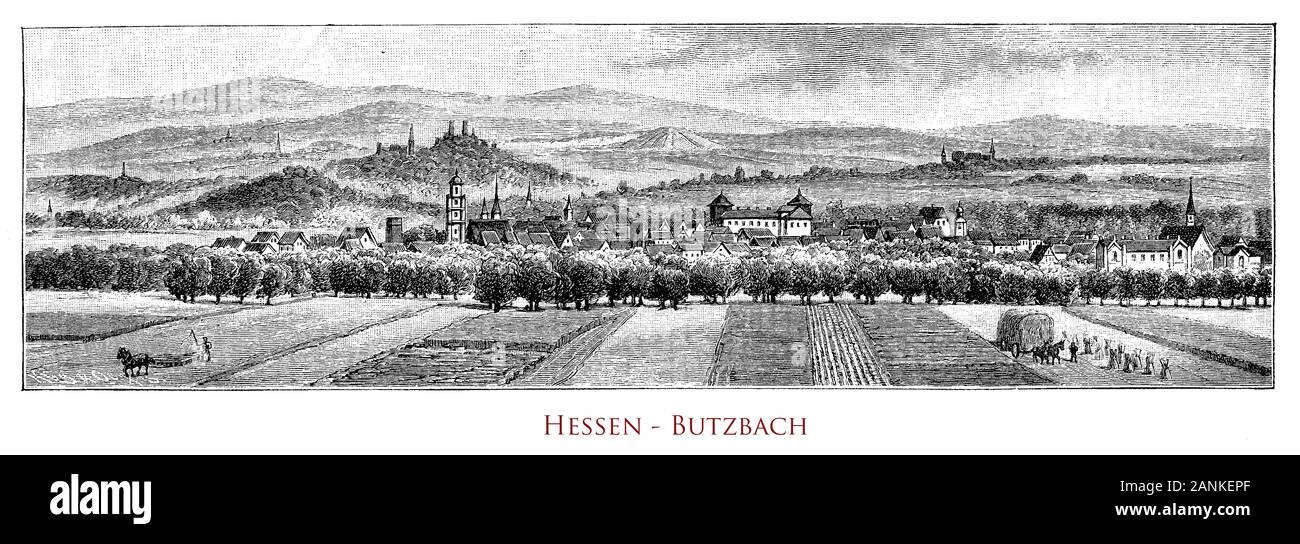 Deutschland, Hessen - Panoramablick auf Butzbach und sein Tal. Die Panoramasicht auf Butzbacher Tal, Deutschland. Der Heidelbeerberg blickt auf die Stadt, ein weiterer deutlich höherer Berg in der Nähe ist der Hausberg mit Aussichtsturm. In der Stadt befinden sich bemerkenswerte alte Rahmhäuser aus dem 16. Jahrhundert und das Landgräberschloss mit dem romantischen Park Stockfoto