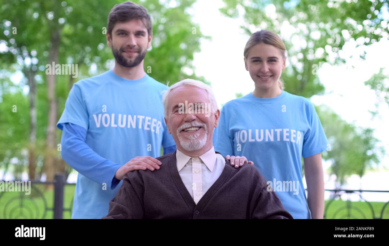 Gerne älterer Mann und zwei Freiwillige in die Kamera lächeln, ältere Menschen unterstützen Stockfoto